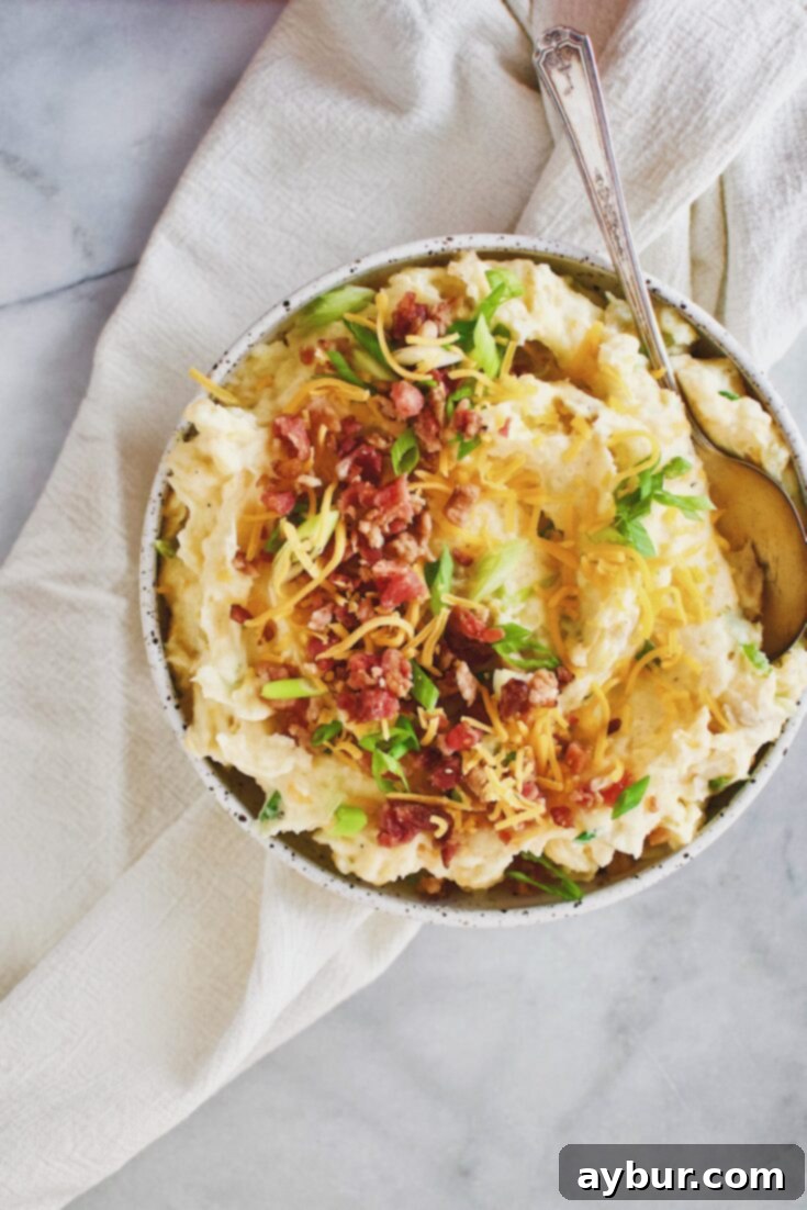 Loaded Baked Potato Mash 9 Loaded Baked Potato Mashers topped with bacon, cheese, and green onions in a serving bowl.