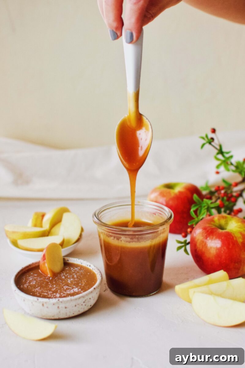 Velvety Homemade Caramel Sauce 4 Close-up of Homemade Caramel Sauce dripping luxuriously from a spoon, ready for dipping apples.