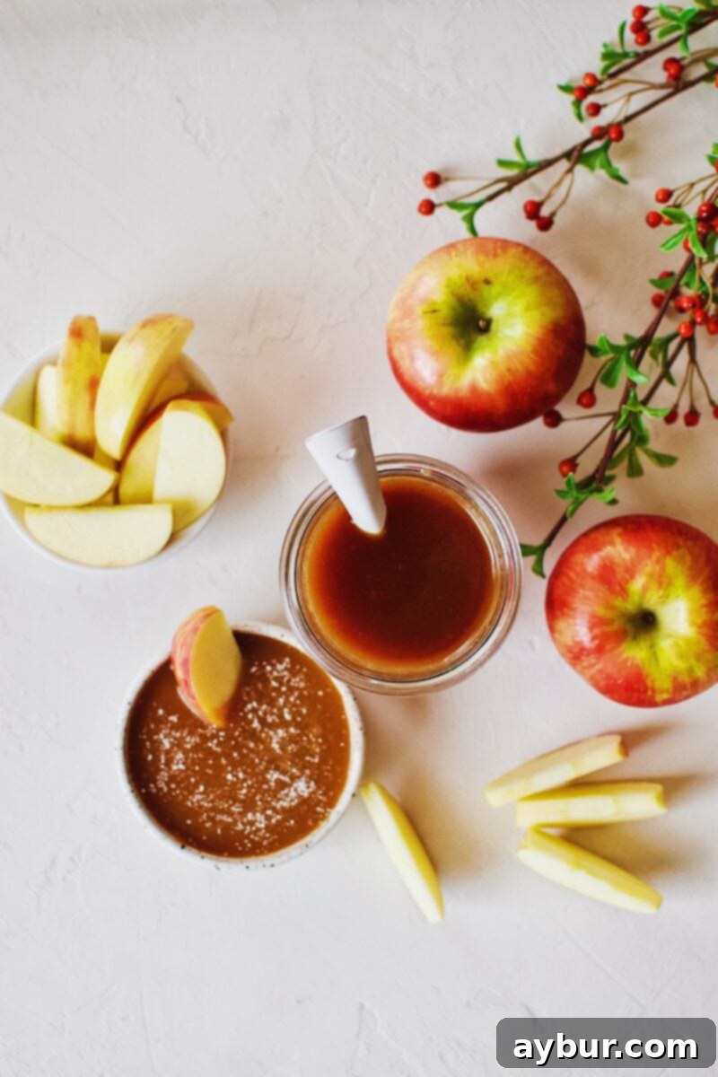 Velvety Homemade Caramel Sauce 5 A jar of freshly made Homemade Caramel Sauce next to a plate of apple slices, ready for a delicious snack.