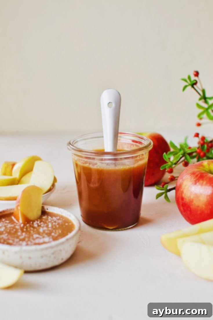 Homemade Caramel Sauce with apples and a spoon, inviting enjoyment.