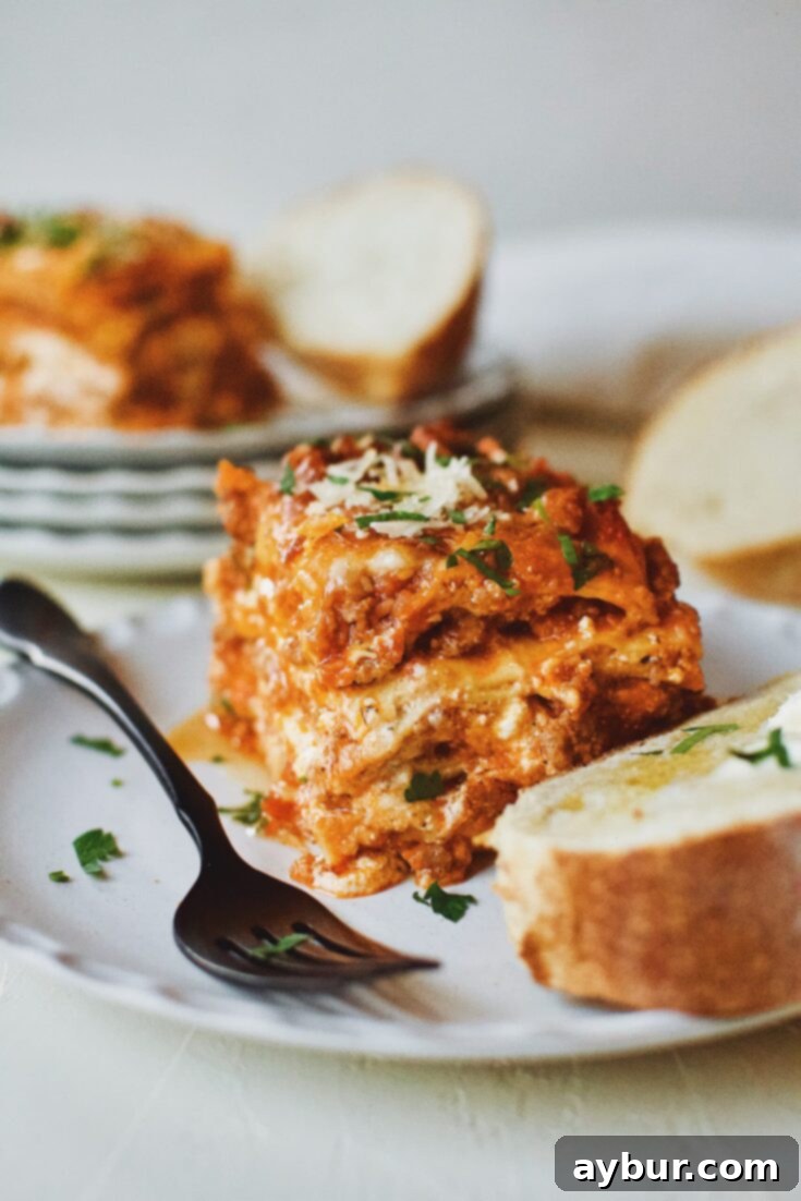 A slice of Homemade Lasagna, accompanied by toasted bread and butter, perfect for a cozy dinner.