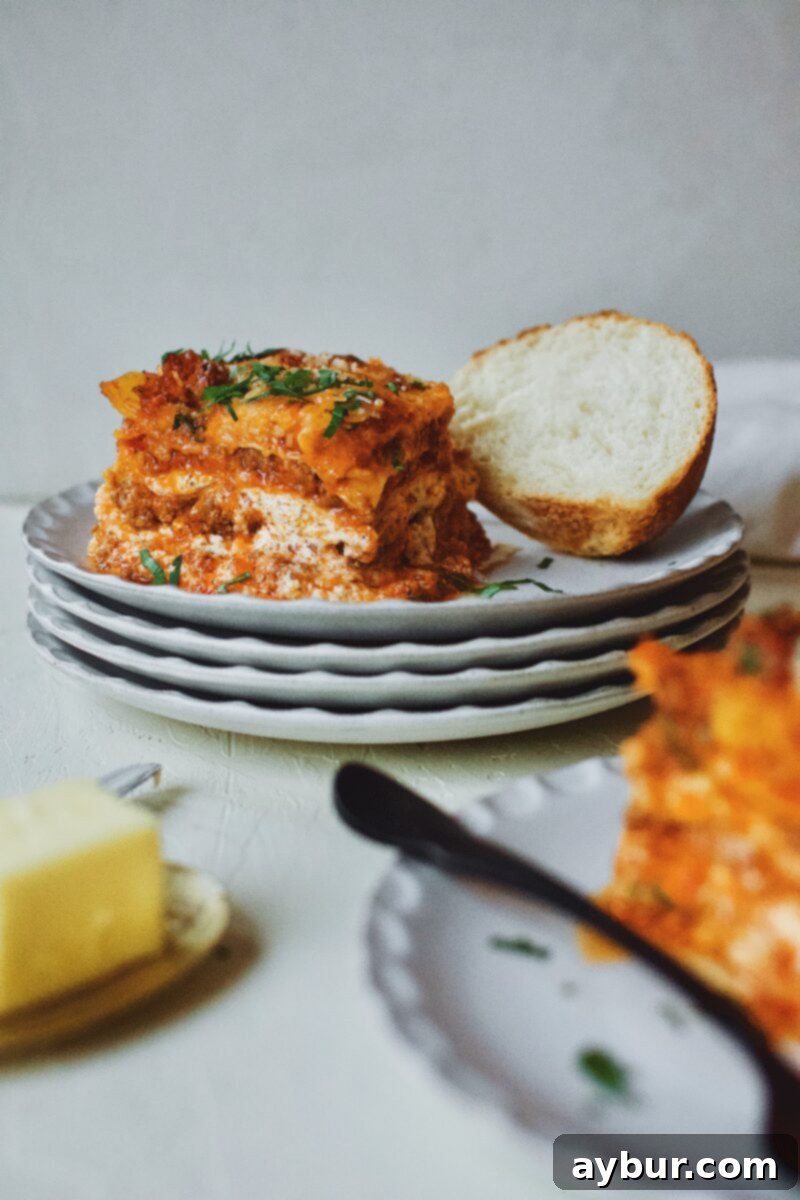 A comforting plate of Homemade Lasagna served with toasted garlic bread and butter, ready to be enjoyed as a hearty meal.