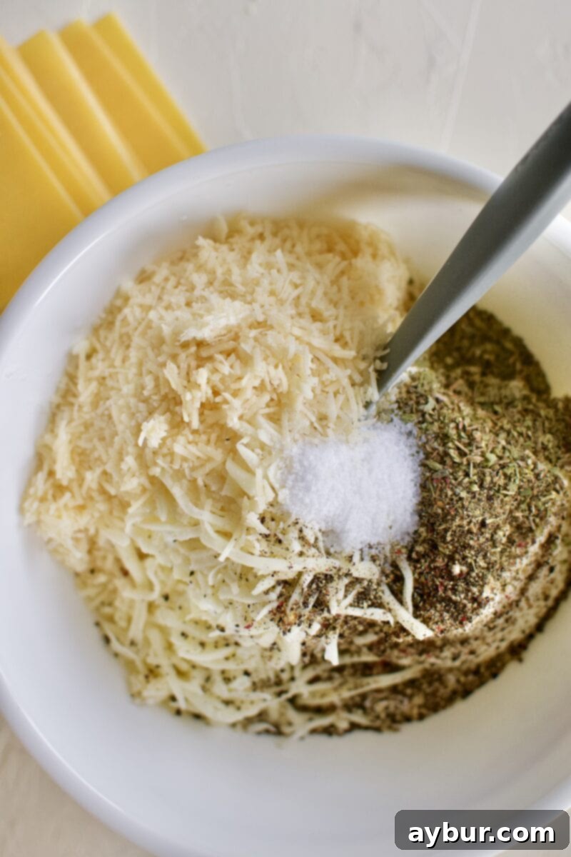 A bowl filled with fresh ricotta, grated parmesan, and shredded mozzarella cheeses, seasoned with salt, black pepper, and Italian herbs, ready to be mixed for the lasagna filling.