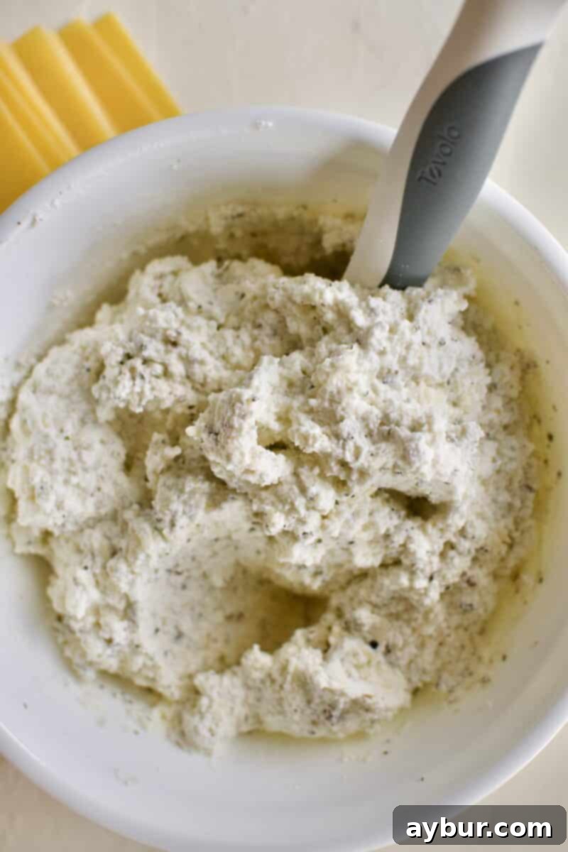 Creamy ricotta, parmesan, and mozzarella cheeses perfectly mixed in a bowl with a blend of salt, pepper, and Italian seasonings, creating a rich and flavorful lasagna layer.