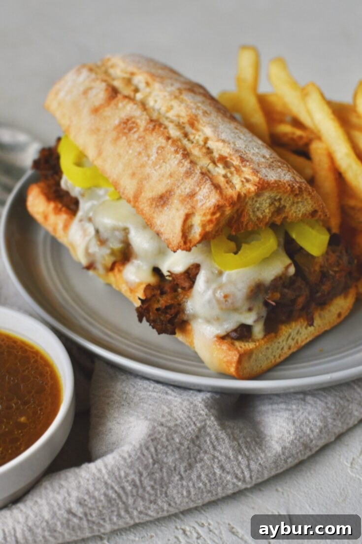 Savory Pot Roast Sandwiches 5 Side view of pot roast sandwiches with jus on the side for dipping and a side of french fries on the plate.