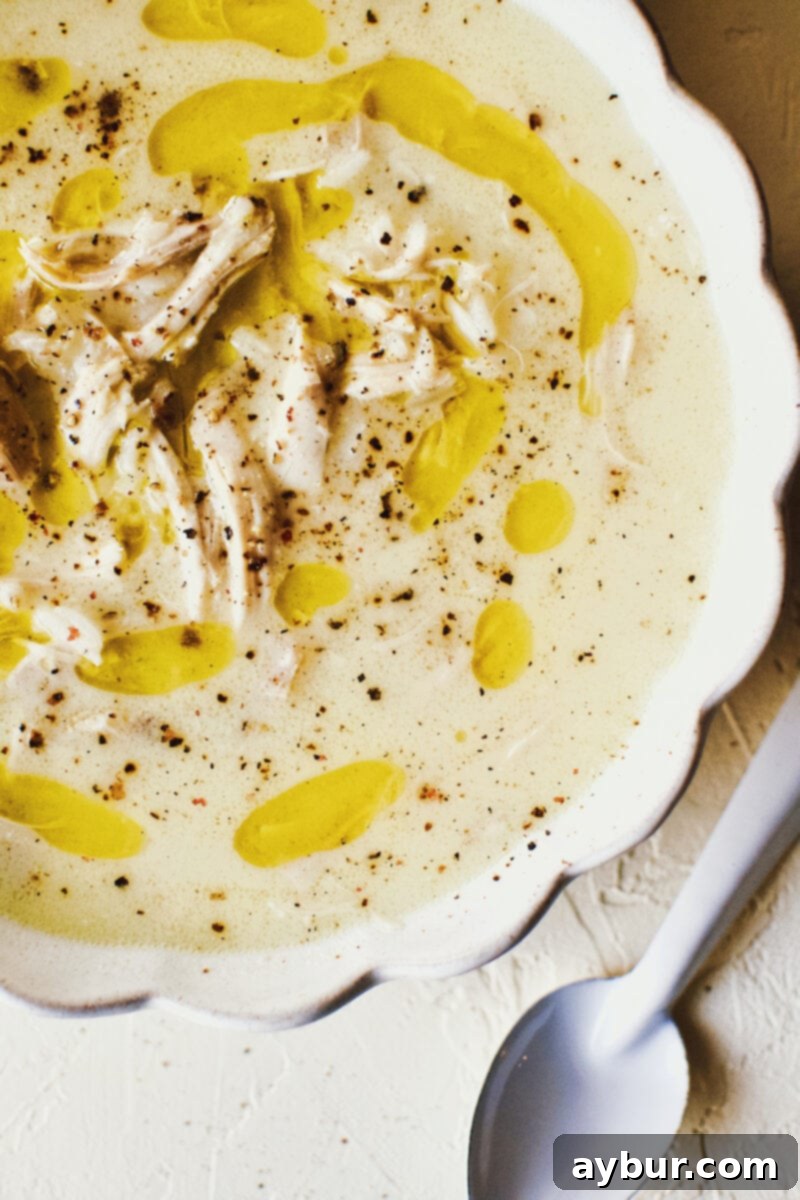 Zesty Greek Avgolemono Chicken Rice Soup 11 A final inviting image of the Lemony Greek Chicken and Rice Soup, featuring a close-up of the broth and ingredients in a white bowl, ready for enjoyment.