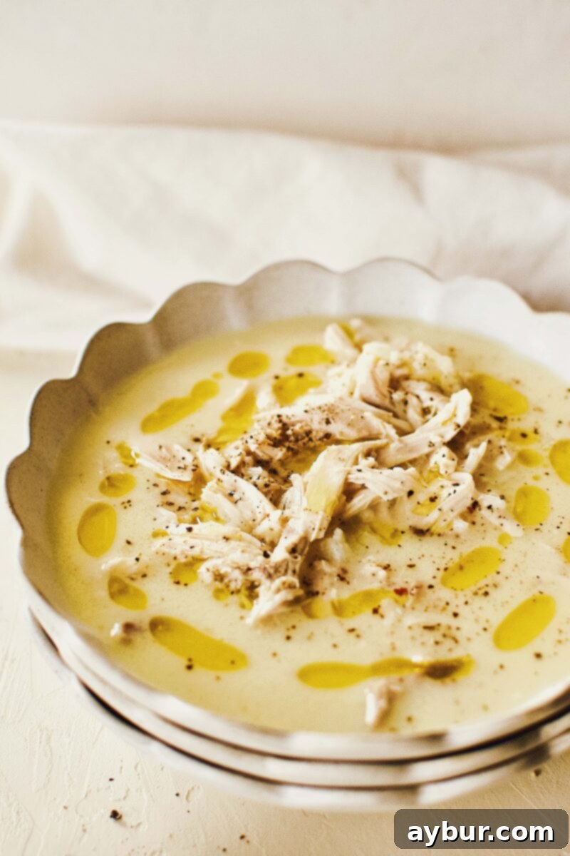 Zesty Greek Avgolemono Chicken Rice Soup 8 Another enticing view of the Greek Avgolemono Lemon Rice Soup in a white bowl, highlighting its creamy consistency and inviting presentation.