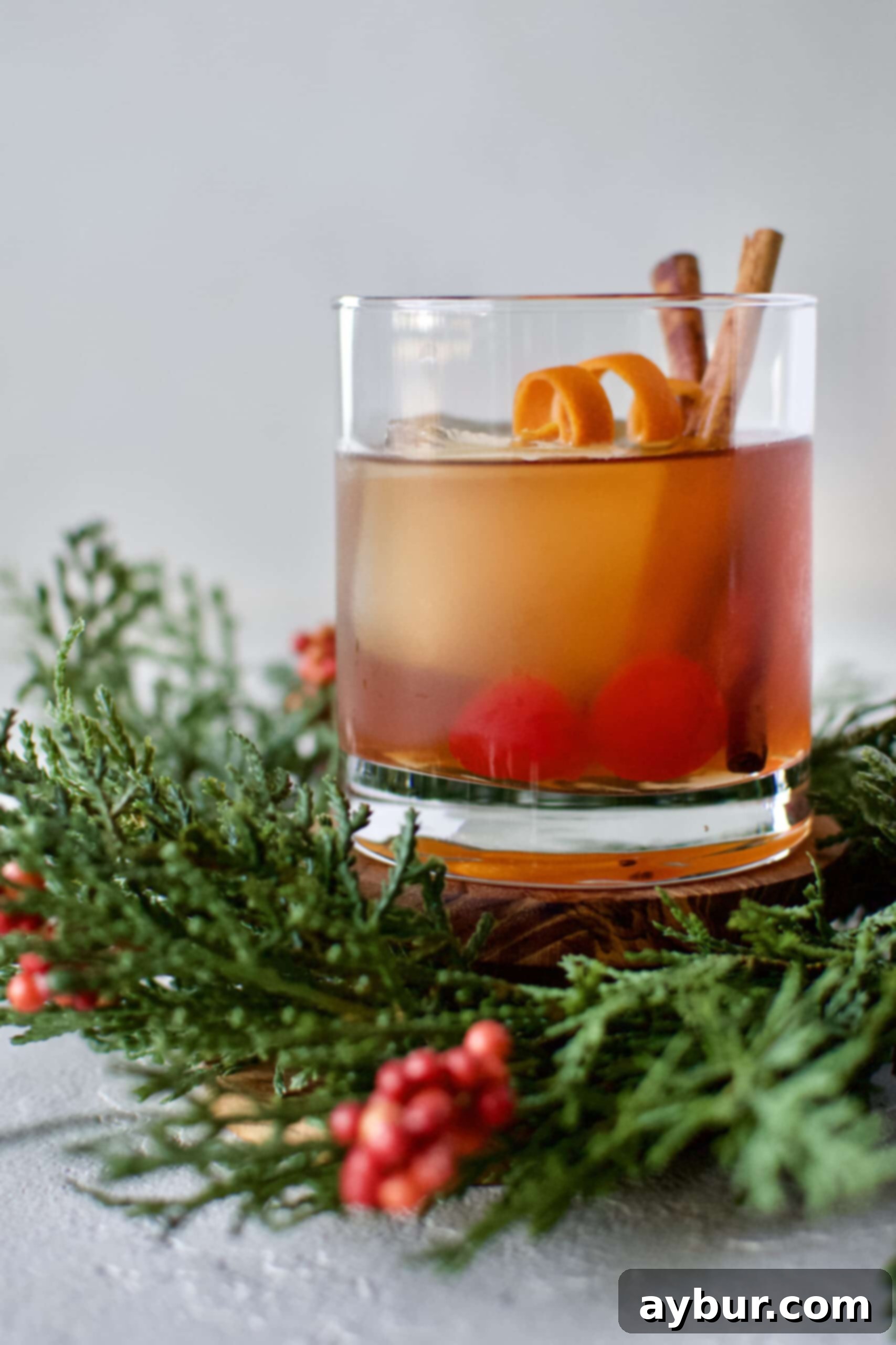 A perfectly prepared Bourbon Brown Sugar Old Fashioned cocktail, ready to be enjoyed. The deep amber liquid glistens with ice, an orange peel twist, and a cinnamon stick garnish, hinting at its rich, aromatic flavor.