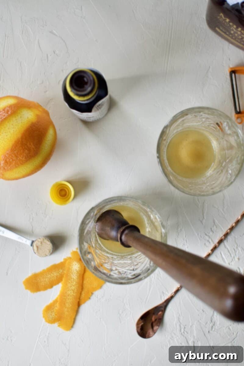 Brown sugar, water, and Angostura bitters muddled together at the base of a glass, forming a rich, dark syrup.