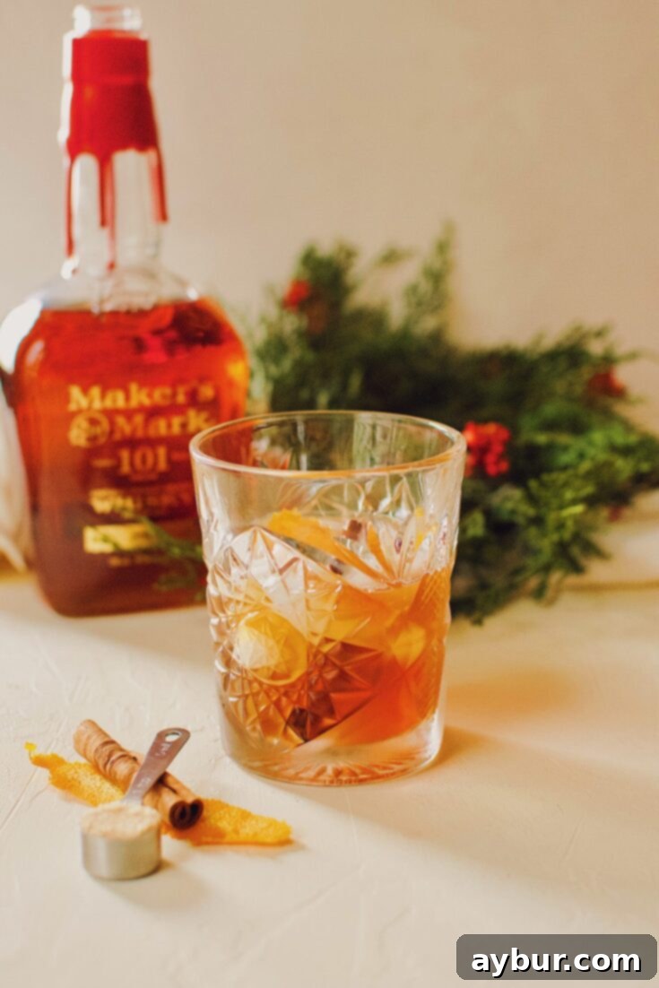 A beautiful Bourbon Brown Sugar Old-Fashioned Cocktail, garnished with an orange peel and cinnamon stick.