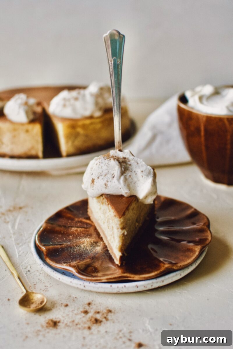 A slice of Chai-Spiced Cheesecake ready to eat with a fork pressed into it, showing the creamy texture and golden crust.