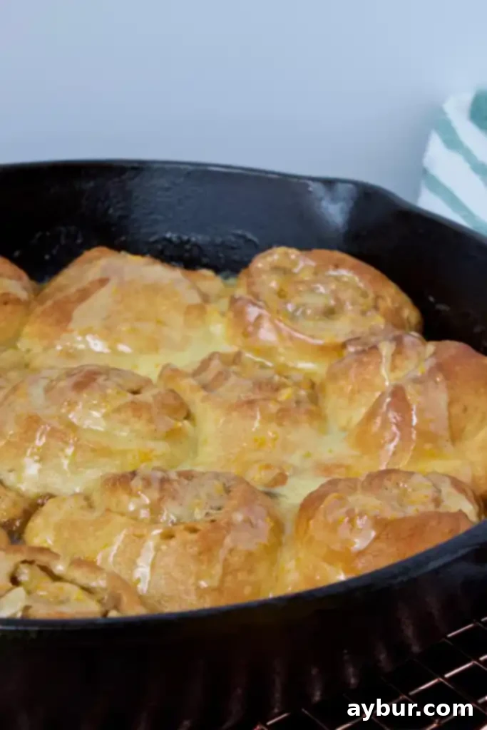 Delicious Quick Orange-Walnut Sweet Rolls on a white plate, drizzled with glaze, ready to be served.
