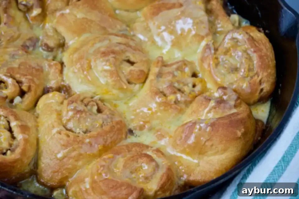 A serving of freshly baked Quick Orange-Walnut Sweet Rolls, showcasing the rich orange glaze and abundant walnut topping.