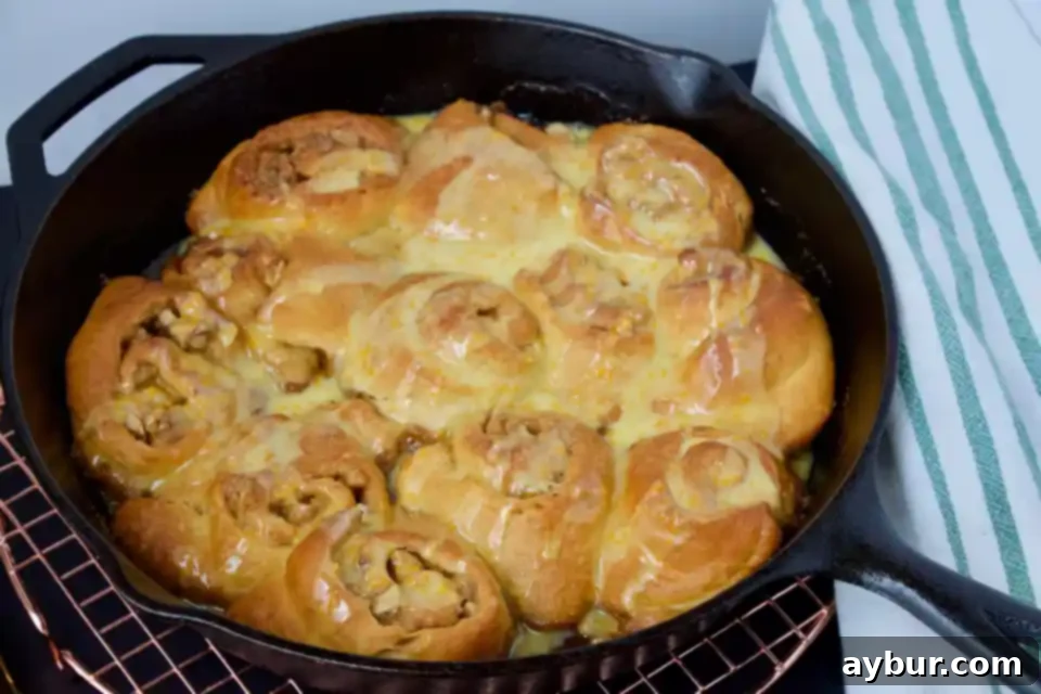Four Quick Orange-Walnut Sweet Rolls arranged on a baking sheet, freshly baked and glistening with glaze, ready to be picked up.