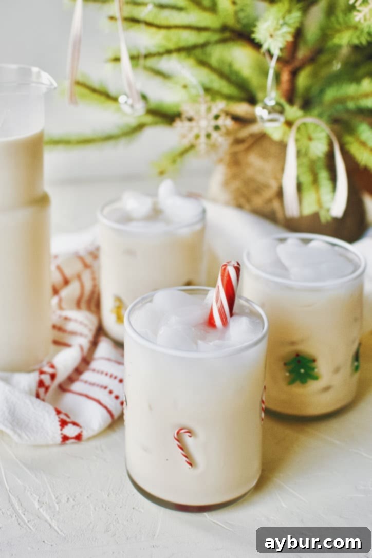 A beautifully garnished Peppermint Chai Eggnog Cocktail in a glass with a candy cane, ready to be enjoyed.