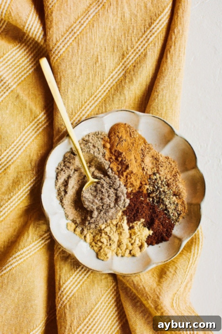 Chai Spice Mix spices portioned out on a plate, with a gold spoon in it ready to stir it up.