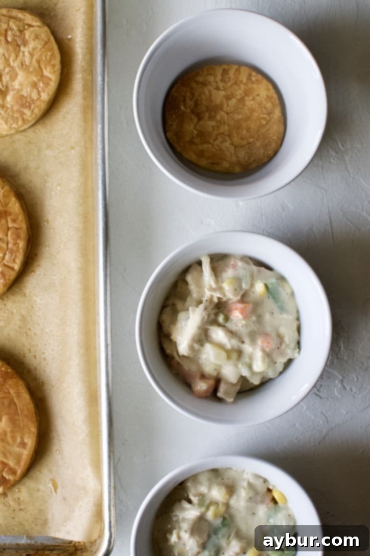 Layering puff pastry rounds and chicken pot pie filling in the serving dish.