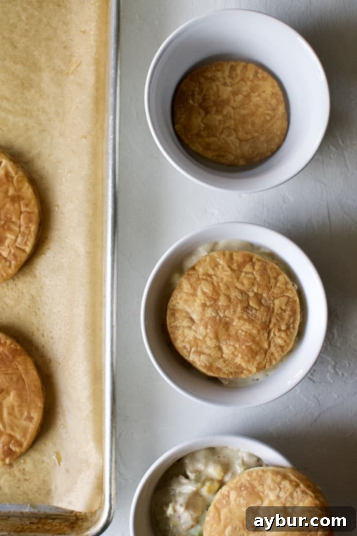 Layering puff pastry rounds and chicken pot pie filling in the serving dish.