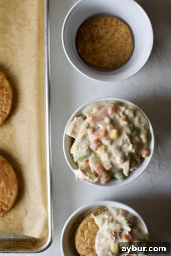 Layering puff pastry rounds and chicken pot pie filling in the serving dish.