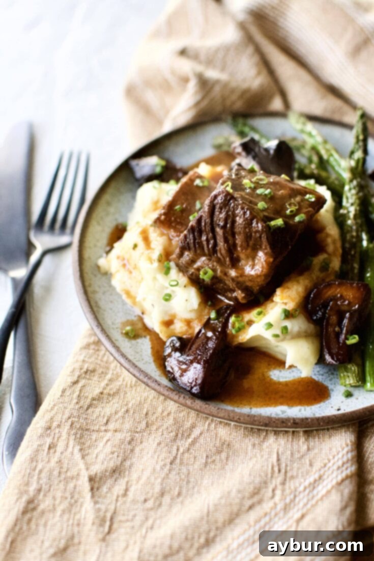 Red Wine Braised Short Ribs on a bed of mashed potatoes with broiled asparagus around them.