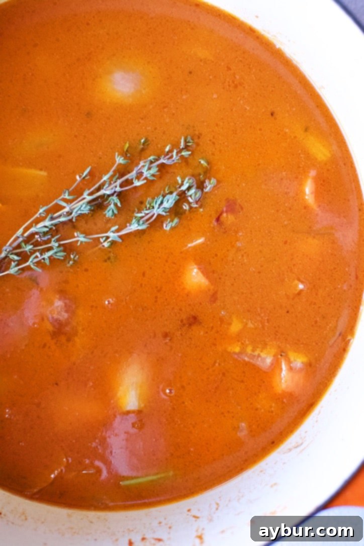 Vegetables deglazed with red wine, tomato paste and chicken stock added to the pot and a sprig of time added.