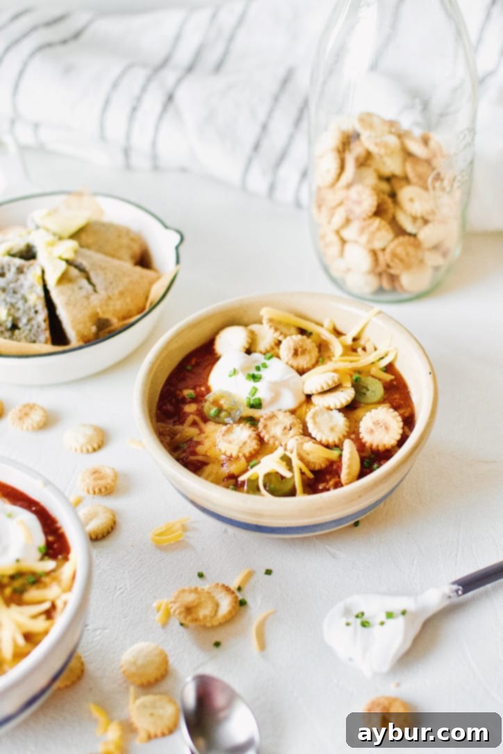 Spicy Texas Chili in two bowls surrounded by various toppings.