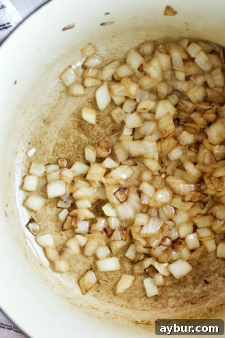 Diced yellow onions sautéing in oil in a large heavy-bottomed pot, turning golden brown.