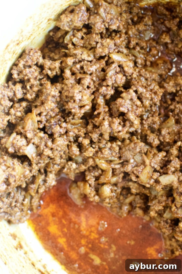The ground beef mixture cooking with spices, becoming fragrant and rich in color.