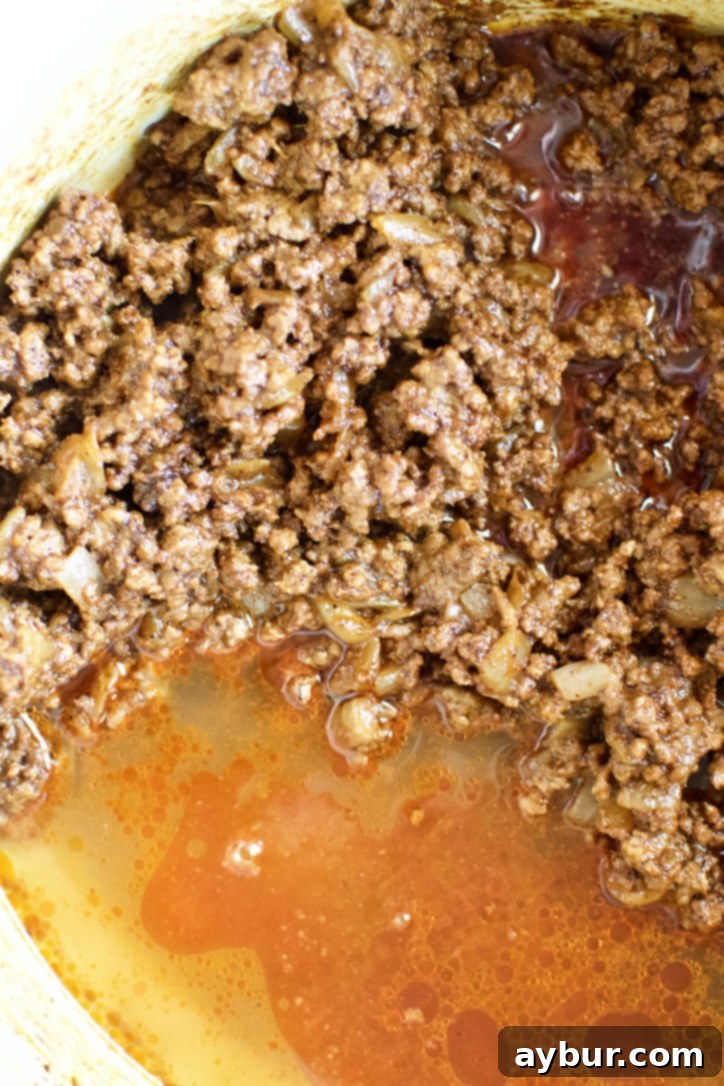 Pouring beef or chicken stock into the pot to deglaze the pan and incorporate all the cooked-on bits.