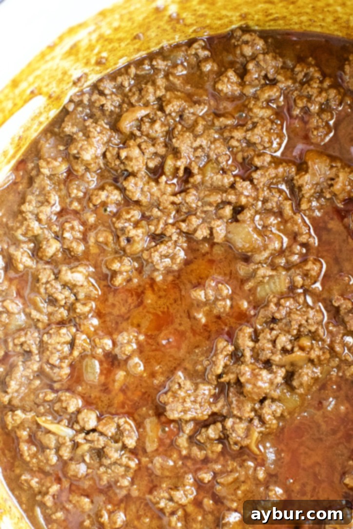 The ground beef mixture simmering in the stock, thickening and developing deep flavors.