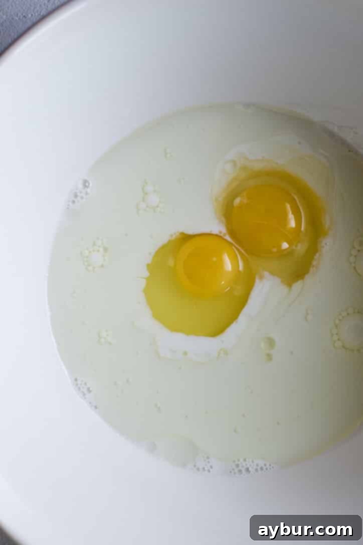 A large bowl containing milk, vegetable oil, and whole eggs before whisking.