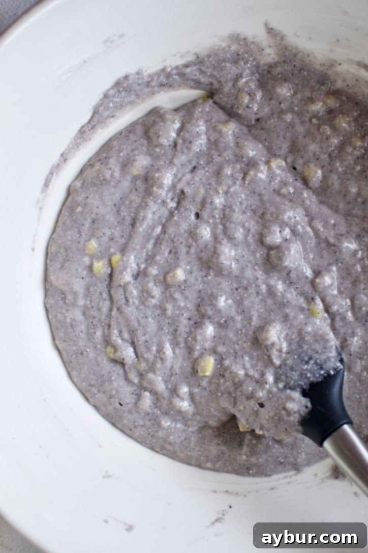 The perfectly mixed blue cornbread batter, gently folded with corn kernels, ready to be transferred to baking pans.