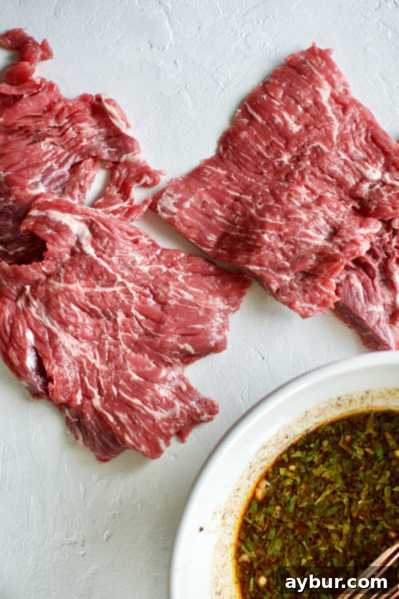 A piece of Beef Loin Flap Meat Steak being added to the Carne Asada Fajita Marinade in a bowl.