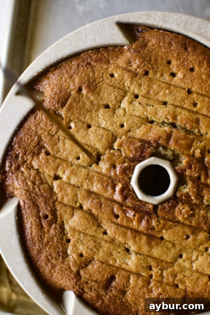 A skewer poking holes into the bottom of the warm cake, preparing it for the whiskey soak.