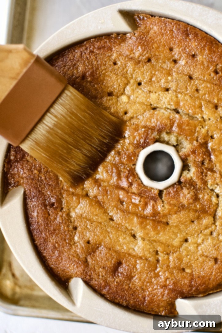 The cake in the pan, absorbing the first layer of whiskey soak through the poked holes.