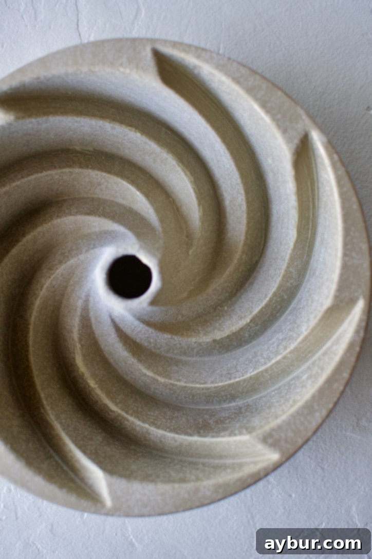 A bundt cake pan, meticulously buttered and lightly floured, ready for the cake batter.