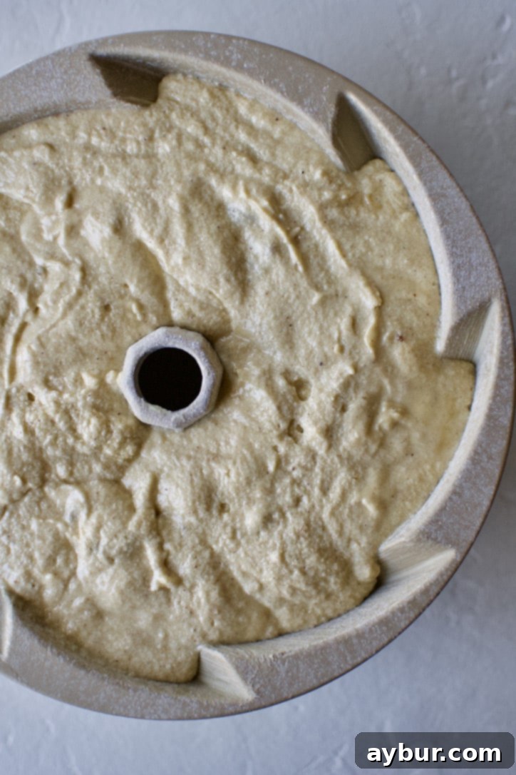 Smooth cake batter perfectly settled into the prepared bundt pan, ready for baking.