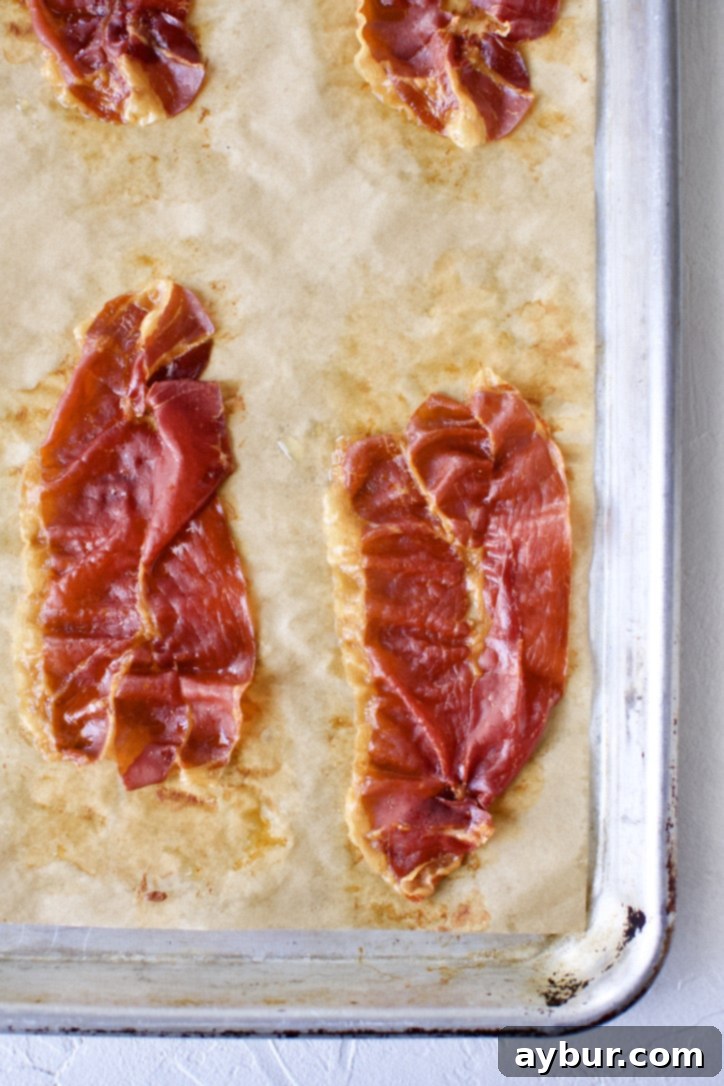 Crispy prosciutto on a parchment-lined baking sheet after baking.