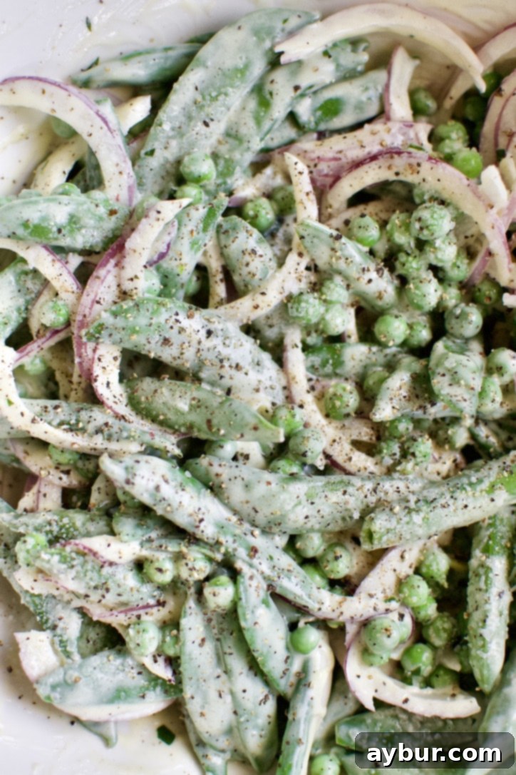 Peas added to the bowl with red onions and seasoned with salt and pepper.