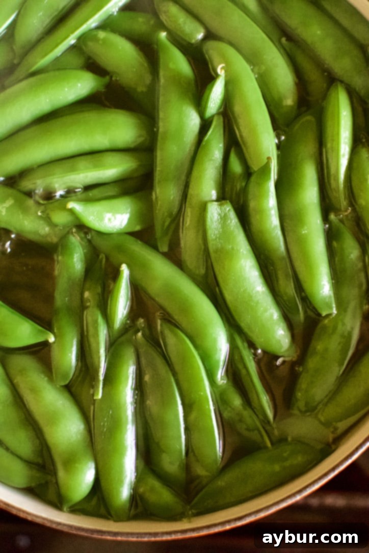 Sugar snap peas cooking in boiling water for blanching.