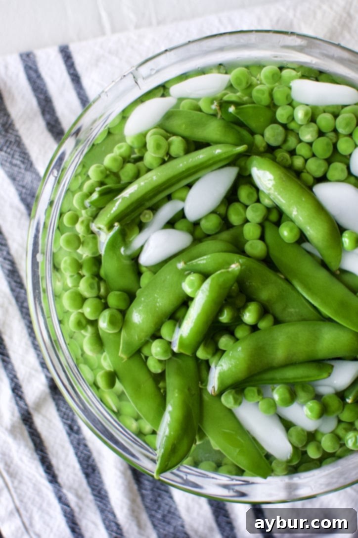 Blanched sugar snap and English peas cooling in an ice water bath.