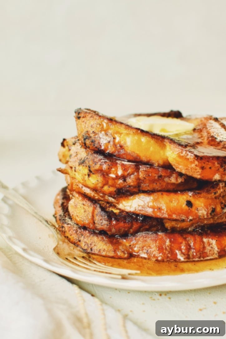 A close-up shot of a single slice of finished Custard French Toast, emphasizing its perfectly golden, caramelized crust and soft, inviting texture.