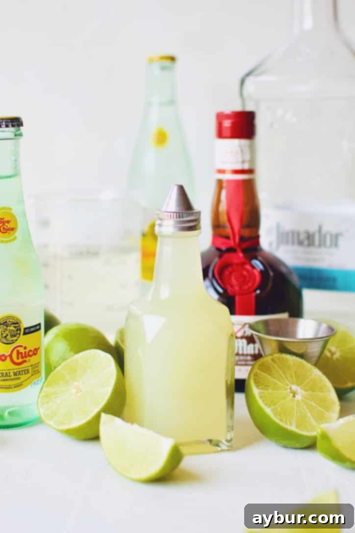All the fresh ingredients laid out: Topo Chico bottles, tequila, lime juice, simple syrup, and fresh limes, ready for mixing a sparkling margarita.