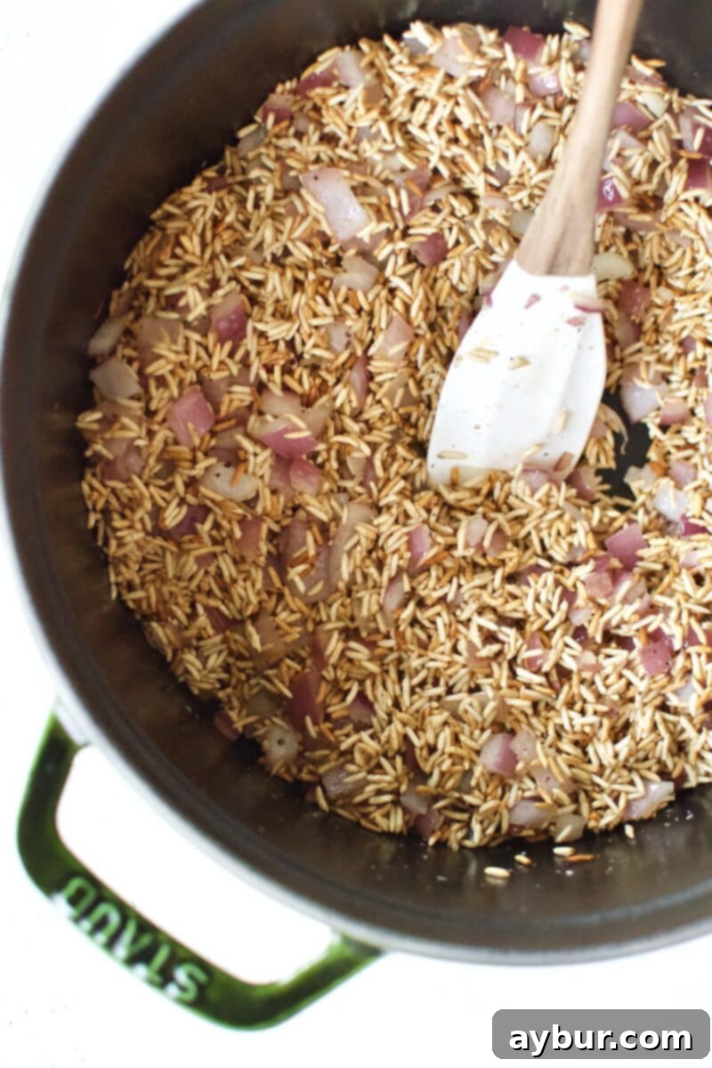 Toasting the rice with the onion and garlic in the bottom of a heavy pot.