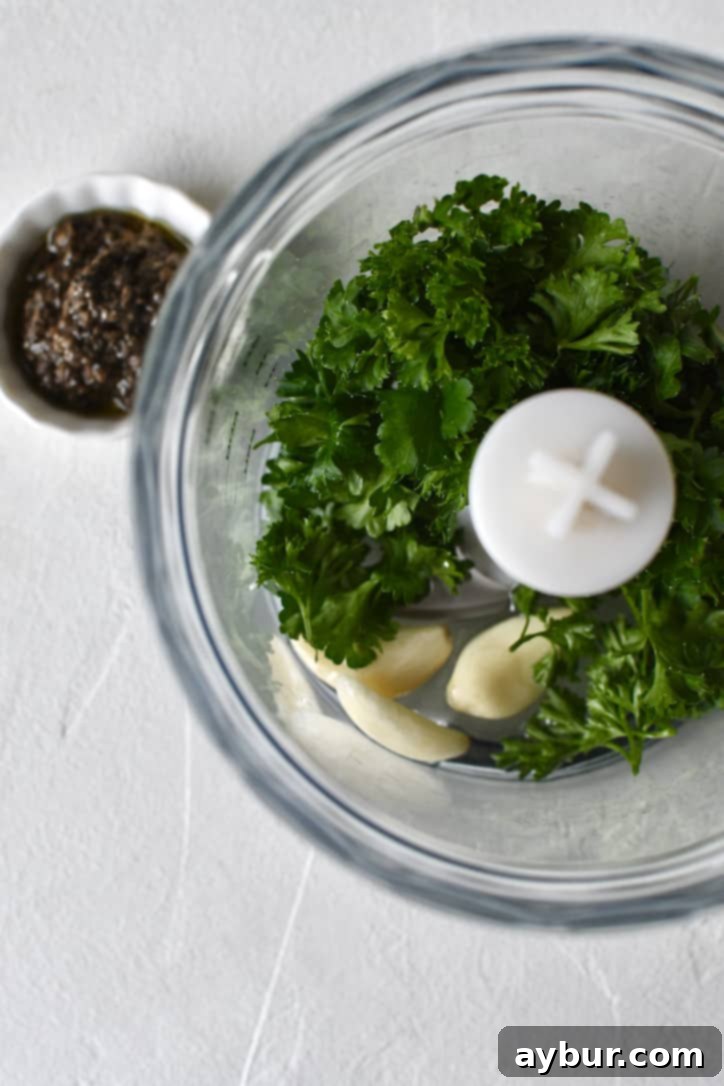 Truffle Fries 4 Garlic, parsley, and white truffle oil, together in a food processor ready to be blended together.