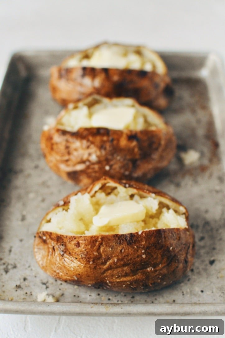 Crispy Skin Baked Potatoes fluffed and topped with butter.