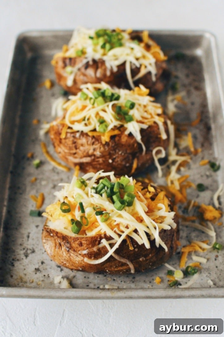 Crispy Skin Baked Potatoes topped with white and sharp cheddar cheeses and green onions.
