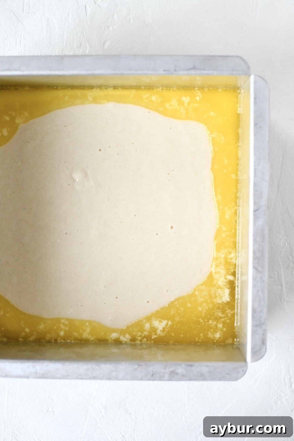 Golden Apricot Cobbler 7 Smooth, light yellow cake batter carefully poured over the melted butter in the baking dish, forming the next layer of the apricot cobbler.