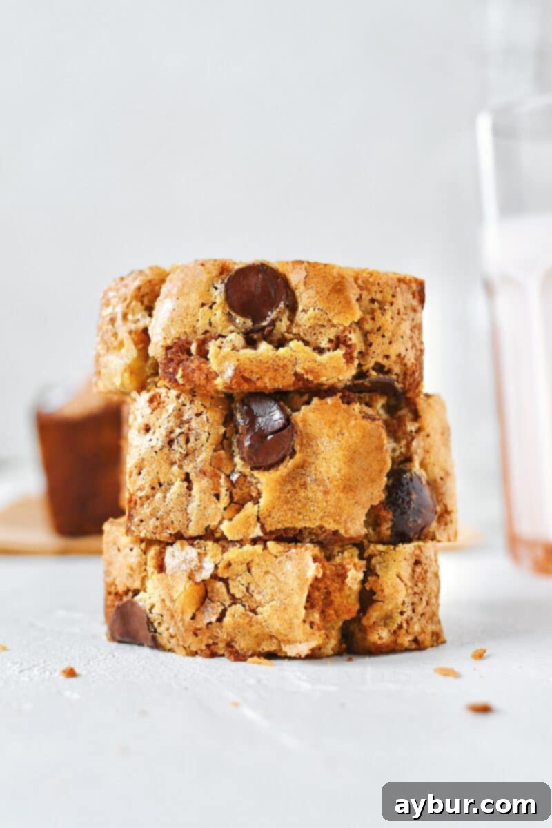 Nutty Brown Butter Banana Loaf 2 Slices of perfectly baked browned-butter banana bread with walnuts and chocolate chips on a rustic plate, next to a glass of milk.