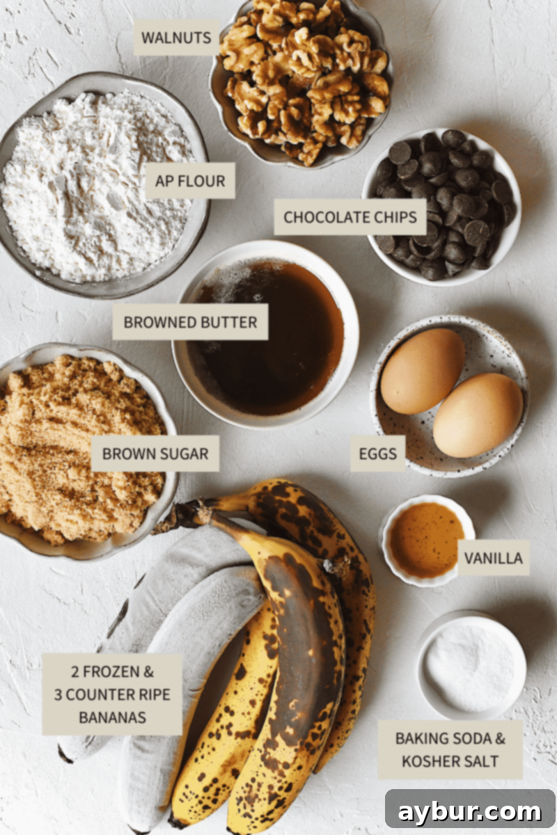 Nutty Brown Butter Banana Loaf 4 A selection of ingredients laid out for baking: a mix of frozen and counter-ripe bananas, browned butter, flour, brown sugar, eggs, vanilla, chopped walnuts, and semi-sweet chocolate chips.